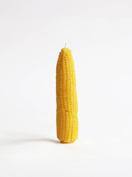 A novelty candle shaped like a corn cob, standing upright on a clean white background.
