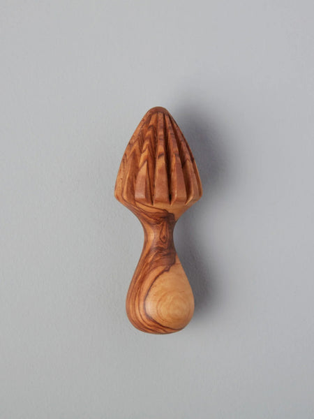 A small wooden citrus juicer with a ribbed cone top and curved handle, shown against a plain light gray background.