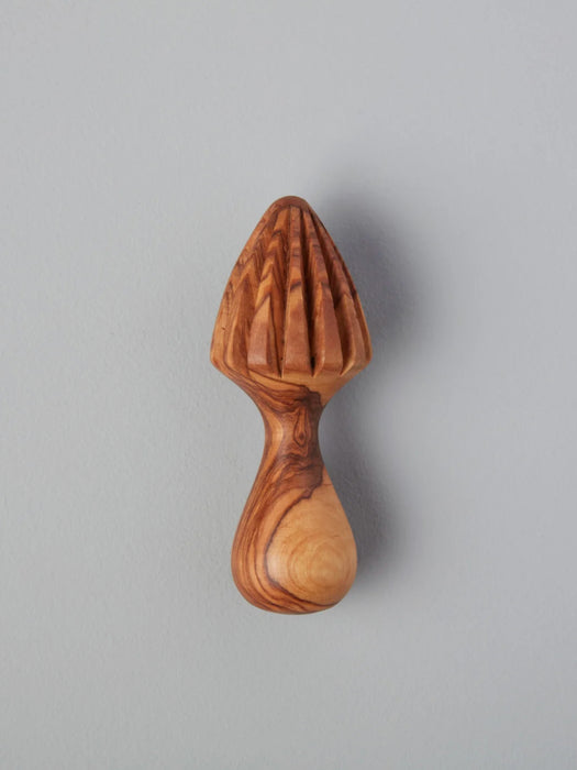 A small wooden citrus juicer with a ribbed cone top and curved handle, shown against a plain light gray background.