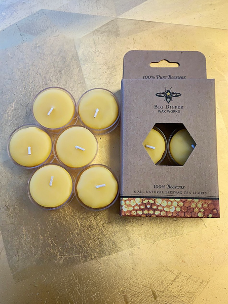 Beeswax tea light candles with a brown cardboard package with a logo of a bee on a gold surface