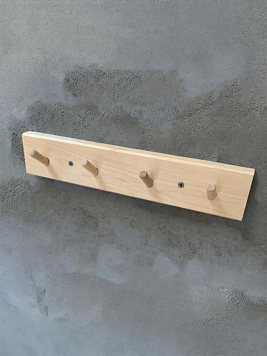 wooden peg hook rack made of light birch wood on a cement grey background.