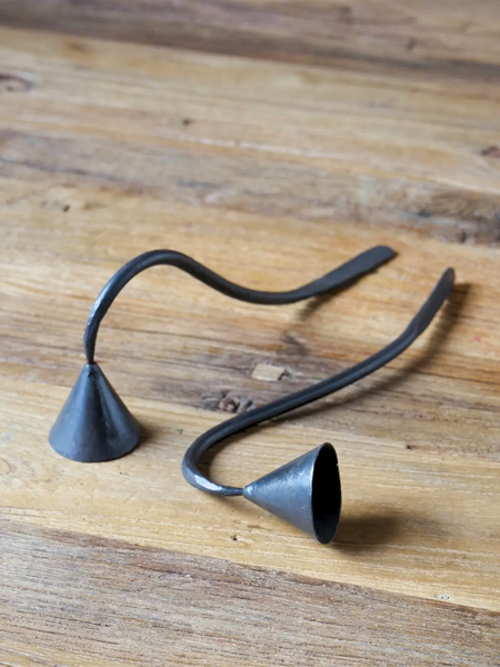Handmade dark metal bell-shaped candle snuffers with curved stems, displayed on a rustic wooden surface.