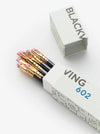A set of 602 black pencils with gold ferrules and pink erasers, shown in their white patterned packaging alongside the open box lid on a clean white background.
