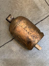 A rustic antique-style bronze bell with a wooden mallet handle, resting on a gray concrete floor.