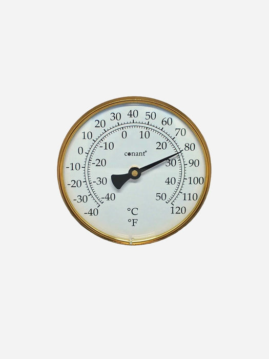 A round analog thermometer with a gold-toned metal frame, white face, black pointer, and black printed temperature markings in Celsius and Fahrenheit, shown against a light gray background.