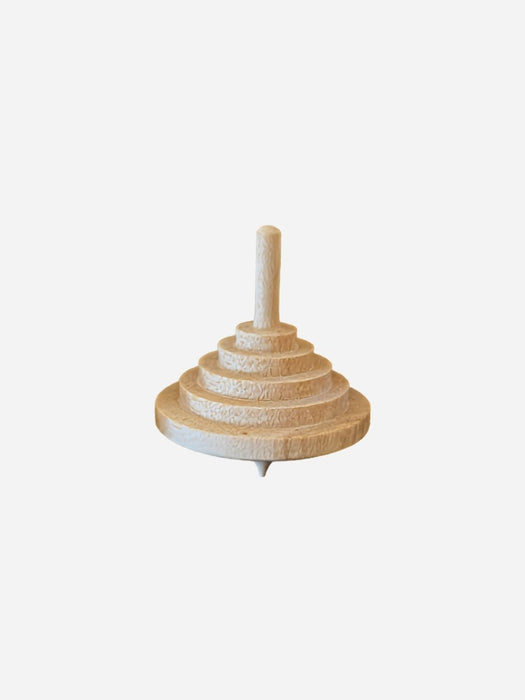 A light natural wood spinning top with a tiered, stacked design and a pointed bottom, shown against a plain light gray background.