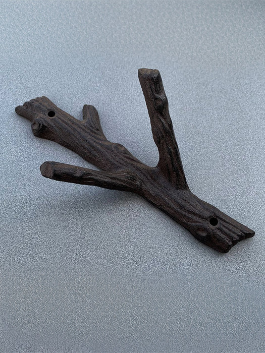A rustic branch-shaped wall hook made from dark wood, featuring a textured bark-like finish and pre-drilled holes, shown on a textured gray background.