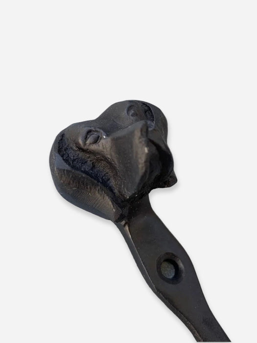 A black cast iron wall hook with a sculpted dog head handle, shown against a plain light gray background.