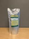 A silver stand-up pouch labeled 'Japanese Spa' standing on a light wood surface against a plain gray wall.
