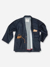 A dark indigo denim jacket from the brand Kith, styled open over a gray knit sweater. The jacket features a collar, front button closure, a chest pocket with a beige leather-like accent, and a large front pocket with a coiled tan rope detail, all laid flat on a white background.