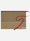 A beige fabric apron with a red waist strap and a red top trim, laid flat on a light gray background. A small white brand label reading 'Niwaki' is visible in the bottom right corner.