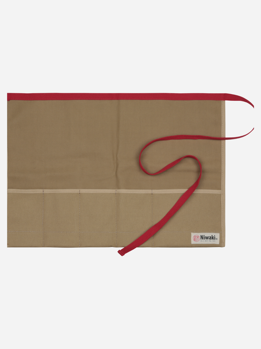 A beige fabric apron with a red waist strap and a red top trim, laid flat on a light gray background. A small white brand label reading 'Niwaki' is visible in the bottom right corner.