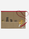 A beige canvas tool roll-up pouch with a red trim and red strap, holding various hand tools including yellow-handled scissors, on a light gray background.
