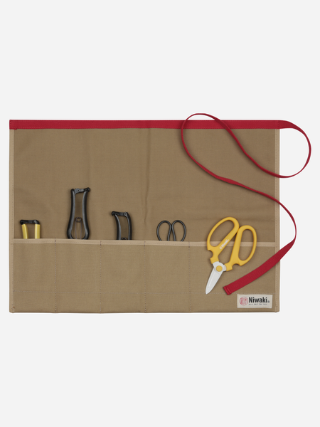 A beige canvas tool roll-up pouch with a red trim and red strap, holding various hand tools including yellow-handled scissors, on a light gray background.
