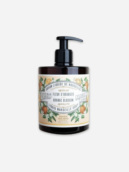 A bottle of Orange Blossom Marseille Soap by Luxe & Floral, featuring a black pump dispenser on an amber glass bottle with a vintage-style cream label decorated with orange blossoms.