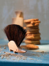 Wooden brush with bristles on a blue surface with cookies in the background