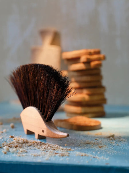 Wooden brush with bristles on a blue surface with cookies in the background