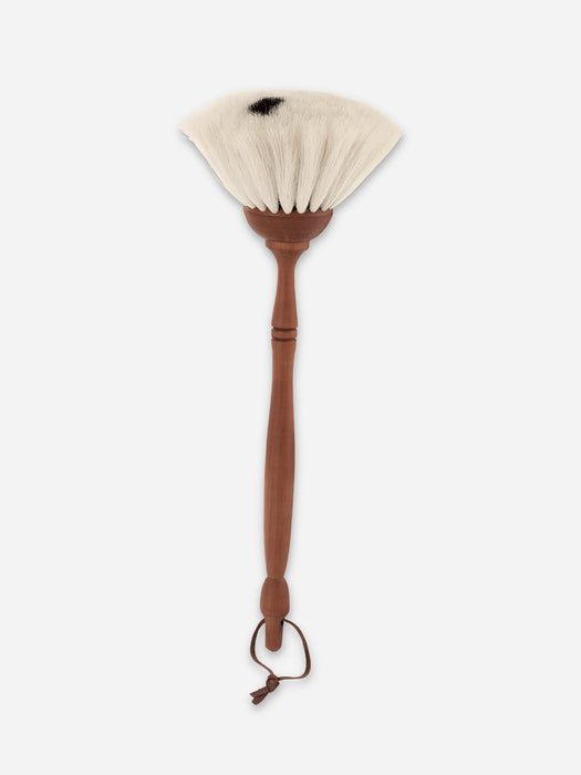 A handmade fan brush with a long brown wooden handle, a small wooden ferrule, and off-white bristles, shown against a light gray background.