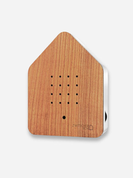 A house-shaped wooden intercom receiver with a warm brown wood grain finish and a white side panel, shown on a light gray background.
