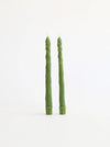 Two tall green asparagus-shaped candles standing upright on a plain white background.