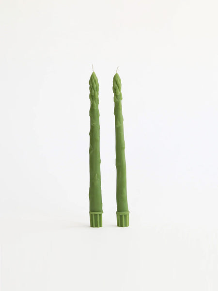 Two tall green asparagus-shaped candles standing upright on a plain white background.