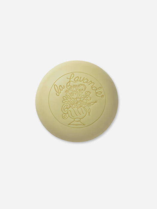 A round, pale yellow bar of soap embossed with the words 'La Lavande' and a floral design, set against a plain white background.